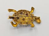 an image of a gold turtle broochle with a red stone in its shell