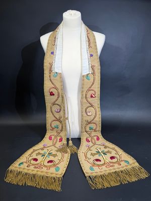 un mannequin blanc orné de franges dorées et de perles colorées