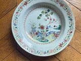 a plate on the floor with flowers and birds painted on it