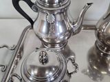 three silver teapots on a silver tray on a table