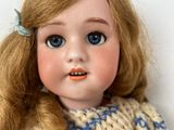 a close up of a doll wearing a sweater and a bow