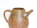 a brown vase that is sitting on a white surface