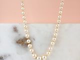 a close up of a pearl necklace on a marble surface