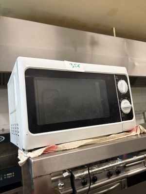 un micro-ondes posé sur une cuisinière dans une cuisine