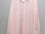 the pink blouse is hanging on a hanger against a wall