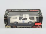 une petite voiture dans une boîte, sur un fond blanc à carreaux noirs et blancs