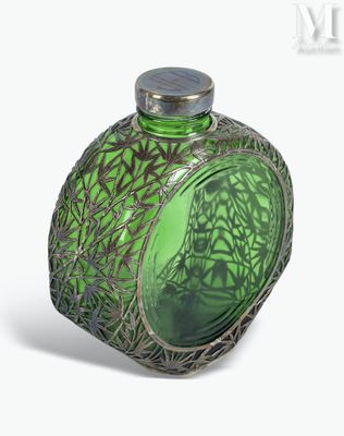 a green glass bottle with a silver lid on a white surface