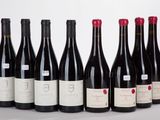 six bottles of wine lined up in a row on a white surface