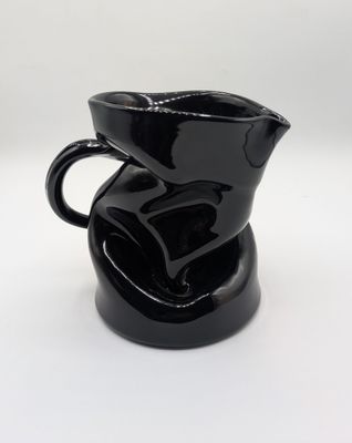 un pichet noir posé sur une table blanche