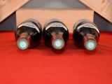 three bottles of wine are lined up on a red cloth