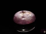 une pomme violette posée sur une surface noire