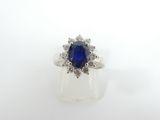 a close up of a blue sapphire and diamond ring on a white surface