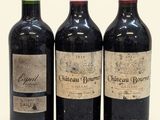 three bottles of red wine sit next to each other on a white surface