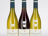 trois bouteilles de vin posées les unes à côté des autres sur une surface blanche