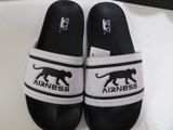 pair of black and white slippers with the word airness on them