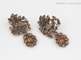two pairs of earrings with flowers on them on a white surface