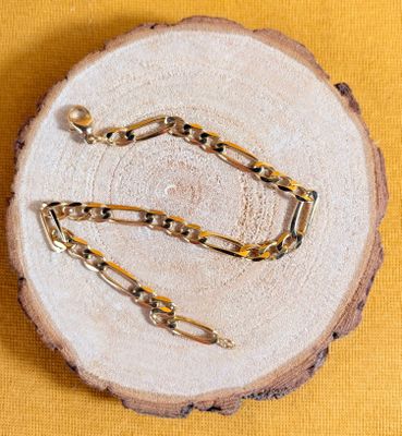 un gros plan sur une paire de chaînes en or posées sur un morceau de bois
