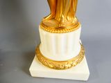a gold statue of a woman on a white pedestal
