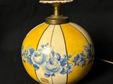 a yellow lamp with blue flowers on it on a black background