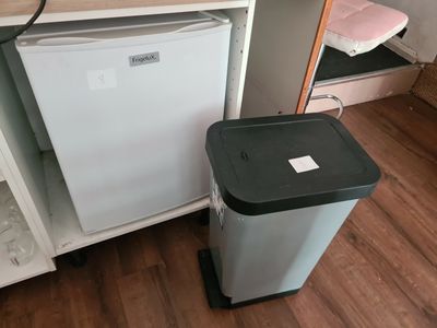 un petit réfrigérateur et une poubelle dans une petite pièce