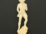 a carved ivory figurine of a man with a hat and a cane