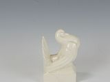 a white sculpture of a bird sitting on top of a book