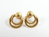 gros plan d'une paire de boucles d'oreilles en or sur une surface blanche