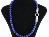 un collier de perles bleues muni d'un fermoir en argent, posé sur un mannequin
