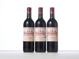 three bottles of red wine sitting on top of a white table