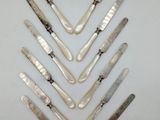 six silver spoons and a knife on a white surface