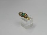 a close up of a gold ring with a green stone on it