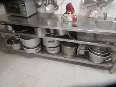 many pots and pans sitting on a stainless steel shelf