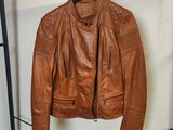 une veste en cuir marron suspendue à un porte-manteau dans une pièce