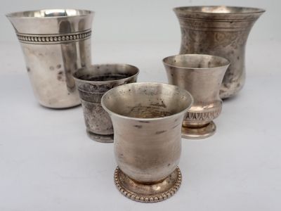 several silver cups are lined up in a row on a white surface