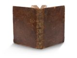 un vieux livre à la couverture brune posé sur une surface blanche