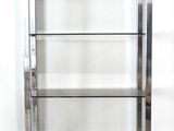 a metal shelf with glass shelves in the corner of a room