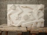 a white sculpture on a wooden bench in front of a brick wall