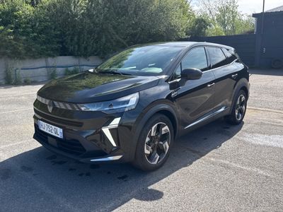 une voiture noire garée sur un parking près d'un mur