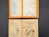 two old books with maps on them sitting on a black surface