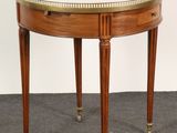 a small round table with a glass top and brass trim