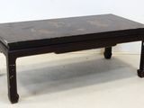 une petite table noire avec un plateau en bois posée sur un sol blanc