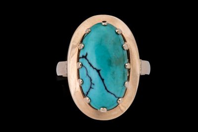 un gros plan d'une bague sertie d'une pierre turquoise sur fond noir