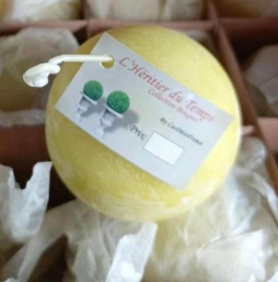 une boule de savon jaune dans une boîte sur laquelle est accrochée une étiquette