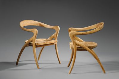 deux chaises en bois avec des accoudoirs et un dossier incurvés