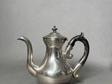 an old silver tea pot with a handle on a table