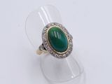 a close up of a ring with a green stone surrounded by diamonds