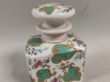 un petit vase blanc et vert avec un couvercle vert