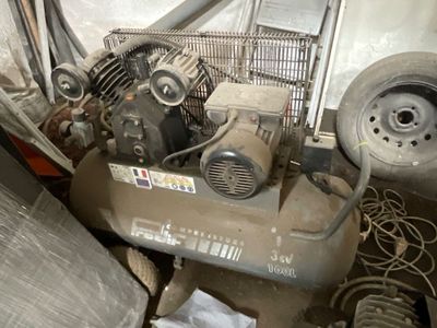 un petit compresseur d'air posé au milieu d'un tas de vieilleries