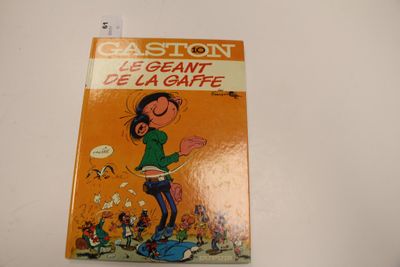un livre orange sur lequel figure un personnage de bande dessinée, posé sur une table