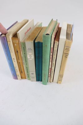 une personne tenant une pile de livres devant un fond blanc